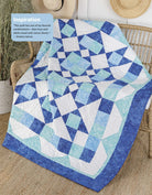 Carmon's Quilt Shop blue and white geometric quilt pattern draped over a wicker chair with a straw hat