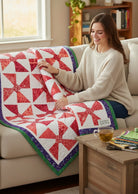 Carmon's Quilt Shop Bold in Bloom quilt pattern featuring a red and white pinwheel design on a lap-sized throw.
