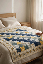Carmon's Quilt Shop Bolero quilt pattern featuring a blue, yellow, and cream floral patchwork design on a bed