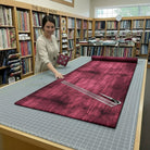 Carmon's Quilt Shop employee measuring a long piece of burgundy wood-textured abstract cotton quilting fabric.