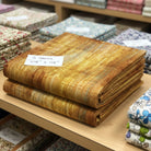 Carmon's Quilt Shop Panorama Carmel wood textured abstract cotton quilting fabric folded on a store shelf.