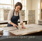 Carmon's Quilt Shop employee cutting mottled charcoal gray 108-inch wide cotton quilt backing fabric with a rotary cutter.