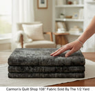Carmon's Quilt Shop charcoal mottled blender 108-inch wide quilting cotton fabric folded on a table