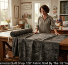 Carmon's Quilt Shop charcoal mottled blender 108-inch wide quilting cotton fabric on a wooden table in a sewing room.