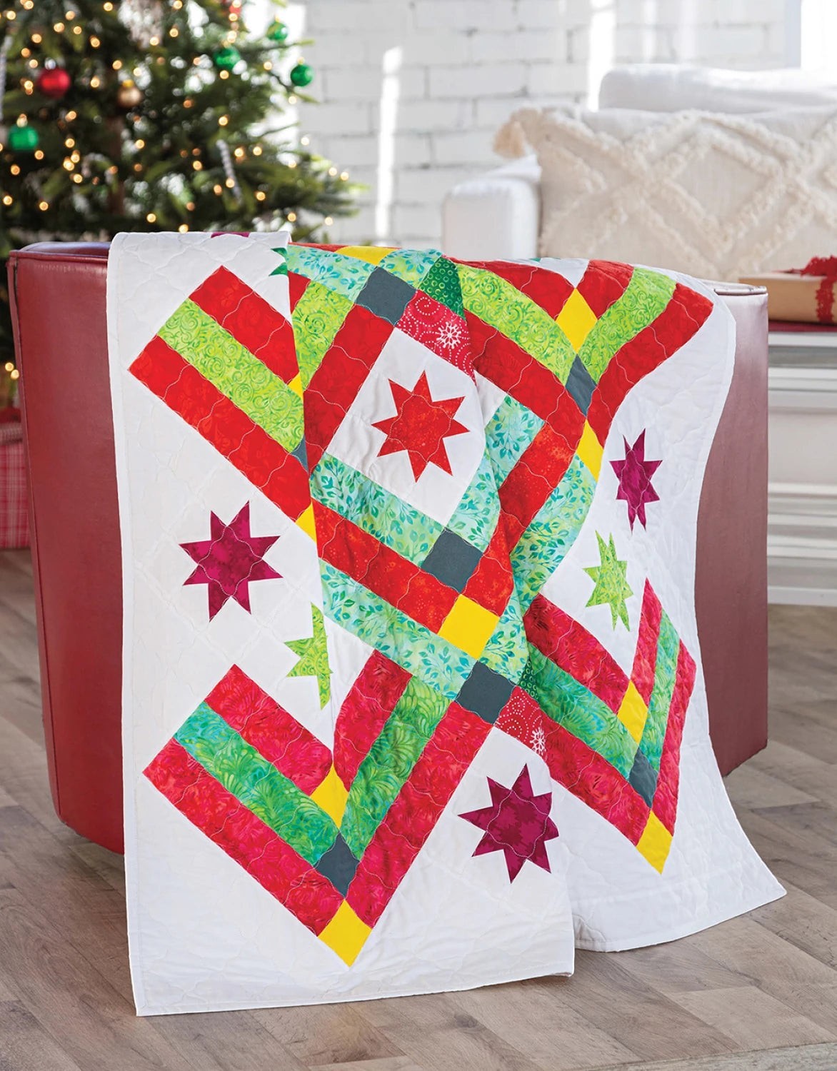 Carmon's Quilt Shop Christmas quilt featuring red, green, and yellow star patterns on a white background