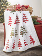 Carmon's Quilt Shop holiday quilt featuring red and green fabric Christmas tree patterns on a white quilted background
