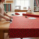 Carmon's Quilt Shop worker cutting red Coca-Cola Christmas logo toss 100% cotton fabric on a wooden table