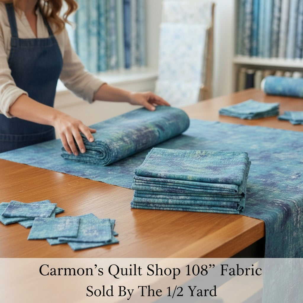 Carmon's Quilt Shop QT Fabrics mottled denim blue 108 inch wide quilting cotton fabric folded on a wooden table.