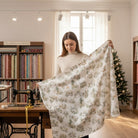Carmon's Quilt Shop Figo Snowbound white cotton fabric with festive holiday print held by a woman in a craft studio.