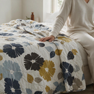 Carmon's Quilt Shop light gray floral vine cotton quilt backing draped over a bed with a person sitting nearby