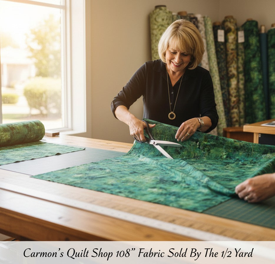 Carmon's Quilt Shop woman cutting forest green mottled 108-inch wide cotton quilting fabric on a wooden table.