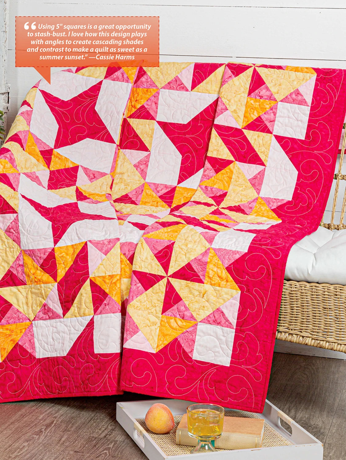 Carmon's Quilt Shop Fun With Squares quilt featuring geometric pink, yellow, and white patterns on a wicker chair.