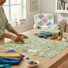 Carmon's Quilt Shop Got Your Back leaf print 108-inch wide green cotton quilting fabric being cut on a wooden table.