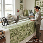 Carmon's Quilt Shop wide green botanical leaf print cotton fabric on a longarm quilting machine in a sewing studio.