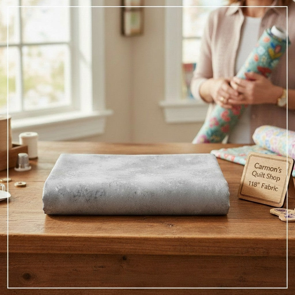 Carmon's Quilt Shop grey Panorama Rapture Blender 118 inch wide cotton backing fabric folded on a wooden table.