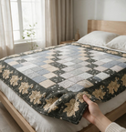 Carmon's Quilt Shop Holiday Flourish quilt featuring a patchwork center and floral border on a bed