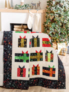 Carmon's Quilt Shop Jelly Roll quilt featuring colorful gift box patterns on a cream background with a black border