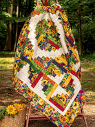 Carmon's Quilt Shop Jelly Roll quilt featuring vibrant sunflower patterns and geometric blocks hanging outdoors