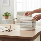 Carmon's Quilt Shop Light As Air 10-inch cotton fabric squares stacked on a table with sewing tools nearby.