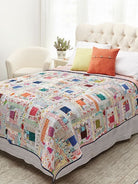 Carmon's Quilt Shop Log Cabin Variations quilt pattern book featuring a colorful patchwork quilt on a bed