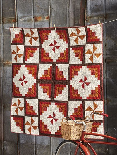 Carmon's Quilt Shop Log Cabin Variations quilt featuring red, orange, and cream geometric fabric patterns.