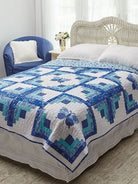 Carmon's Quilt Shop Log Cabin Variations quilt featuring blue and white butterfly patterns on a bed in a bedroom.