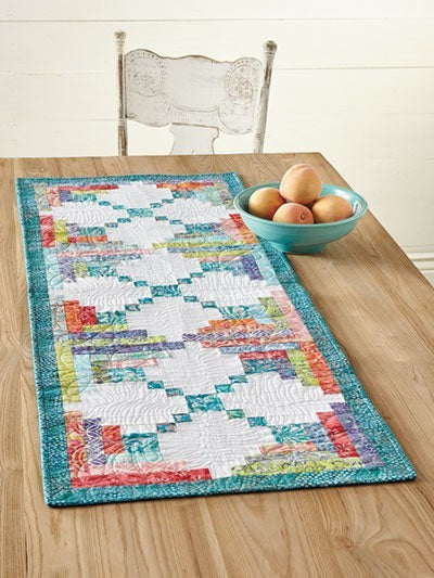 Carmon's Quilt Shop Log Cabin Variations table runner featuring colorful patchwork blocks on a wooden table.