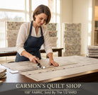 Carmon's Quilt Shop artisan cutting mottled gray 108-inch wide QT Fabrics quilting cotton on a cutting mat.