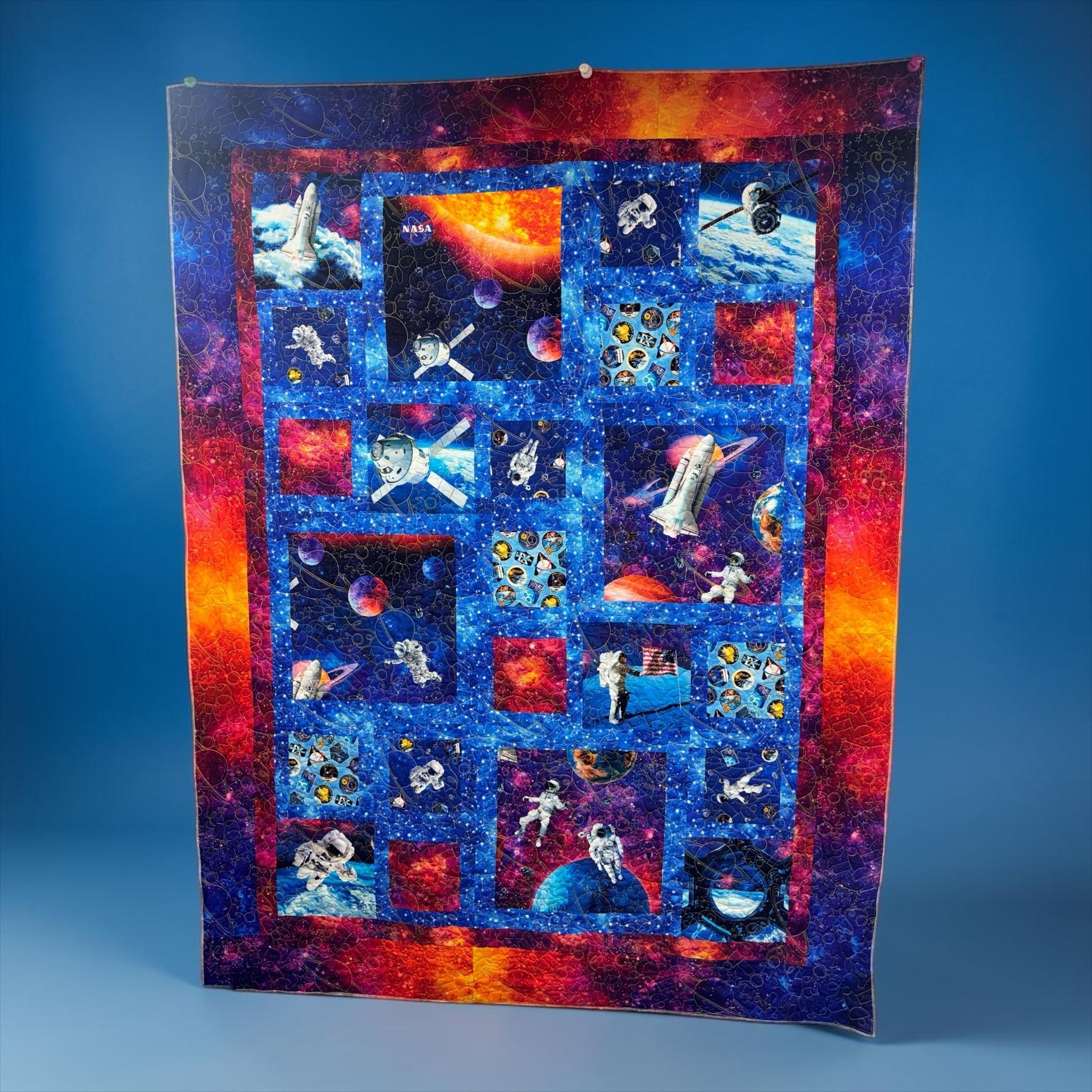 Carmon's Quilt Shop Space Odyssey Hopscotch NASA quilt featuring vibrant space imagery, astronauts, and rockets.