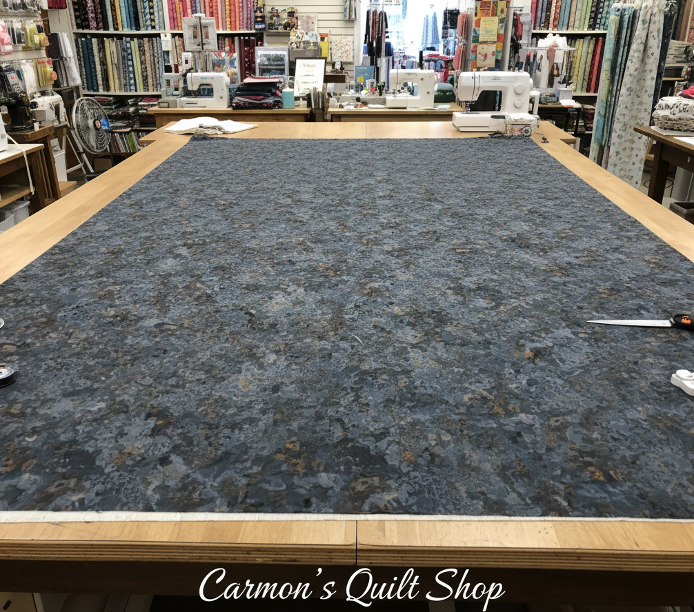 Carmon's Quilt Shop Chroma Obsidian black textured 108-inch wide cotton quilt backing fabric on a cutting table.
