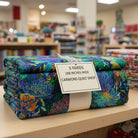 Carmon's Quilt Shop Ocean floral multi-colored 108-inch wide premium cotton quilt backing fabric folded on a shelf.