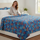 Carmon's Quilt Shop Oceana Coral 108 inch fabric quilt featuring orange and blue coral reef patterns on a blue bed