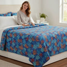 Carmon's Quilt Shop Oceana Coral 108 inch cotton fabric quilt with orange and blue reef print on a made bed