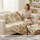 Carmon's Quilt Shop 118 inch wide Panorama tonal floral cotton fabric draped over a sofa with a woman sitting nearby