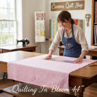 Carmon's Quilt Shop artisan measuring pink daisy scroll blender cotton fabric for a quilting project in a studio