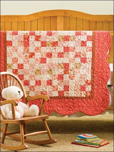 Carmon's Quilt Shop keepsake baby quilt pattern book featuring a pink and cream patchwork quilt with scalloped edges