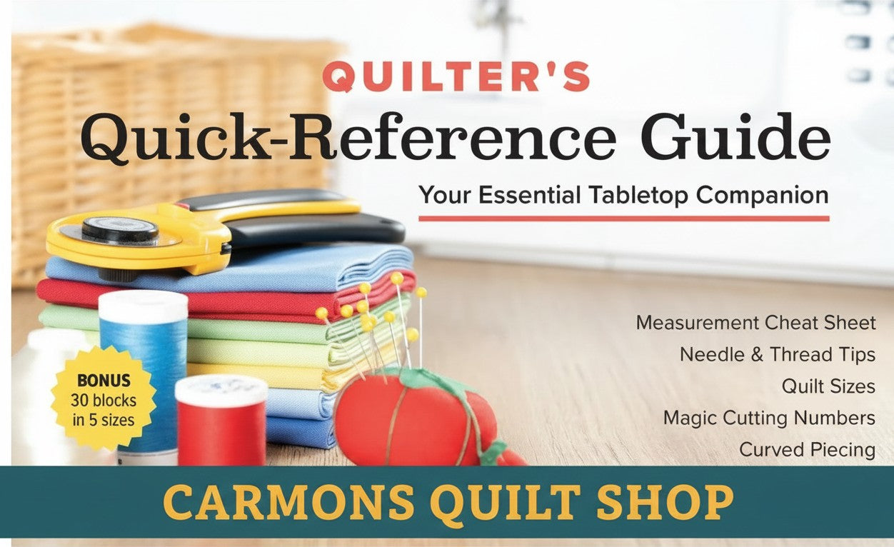 Carmon's Quilt Shop Quilter's Quick-Reference Guide with rotary cutter, fabric stack, and pincushion on a desk.