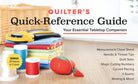 Carmon's Quilt Shop Quilter's Quick-Reference Guide tabletop book with sewing tools, fabric, and pin cushion.