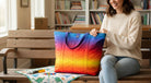 Carmon's Quilt Shop rainbow ombre quilted tote bag held by a woman sitting on a wooden bench.