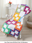 Carmon's Quilt Shop For the Love of Precuts pattern book quilt featuring a colorful rainbow block design on a chair