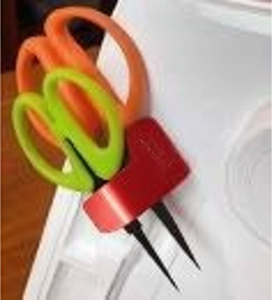 Carmon's Quilt Shop red Sew Very Smooth scissor holster holding orange and green scissors on a sewing machine