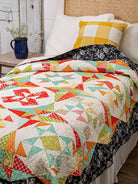 Carmon's Quilt Shop Mix & Match Quilt Sampler book featuring a colorful star-patterned quilt on a bed.