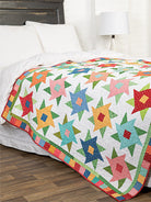 Carmon's Quilt Shop Scrap-Happy quilt pattern book featuring a colorful star-patterned quilt on a bed