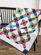 Carmon's Quilt Shop Scrap-Happy quilt pattern book featuring a colorful nine-patch scrap quilt on a black chair