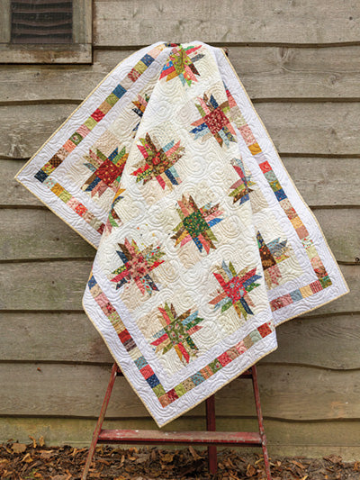 Carmon's Quilt Shop Scrap-Happy quilt featuring colorful star blocks on a cream background with intricate quilting