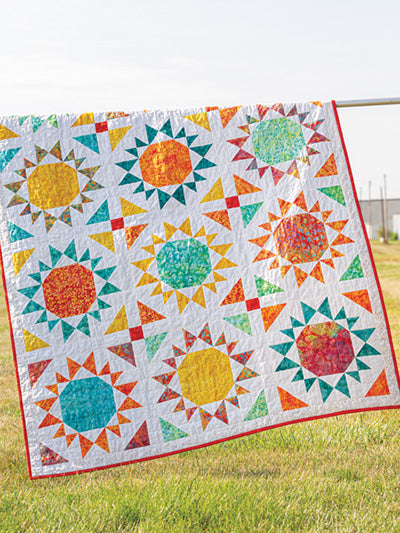 Carmon's Quilt Shop Scrap-Happy quilt pattern featuring a colorful sunburst design on a white background