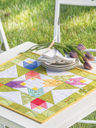Carmon's Quilt Shop Scrap-Happy quilt pattern featuring a colorful star design on a white table with tulips