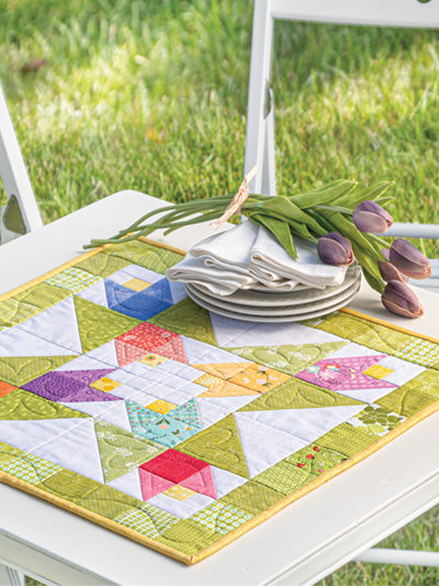 Carmon's Quilt Shop Scrap-Happy quilt pattern featuring a colorful star design on a white table with tulips