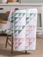 Carmon's Quilt Shop Scrap-Happy quilt featuring green and pink floral triangle patterns draped over a wooden chair