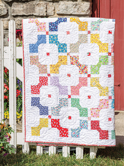 Carmon's Quilt Shop Scrap-Happy quilt featuring colorful floral fabric scraps and white background with swirl quilting